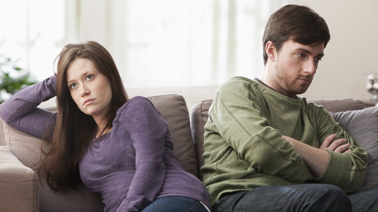 Married couple ignoring each other while sitting on the couch