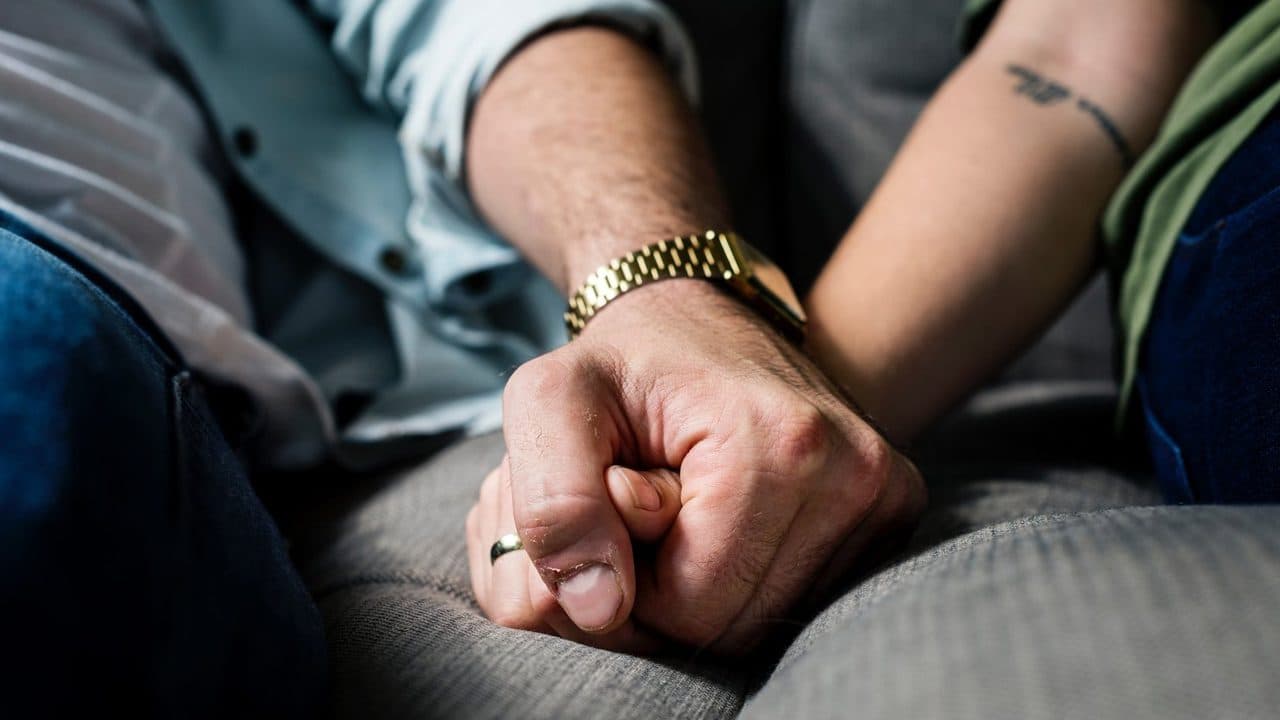 Married couple holding hands on the couch