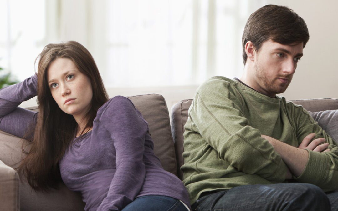 Married couple ignoring each other while sitting on the couch