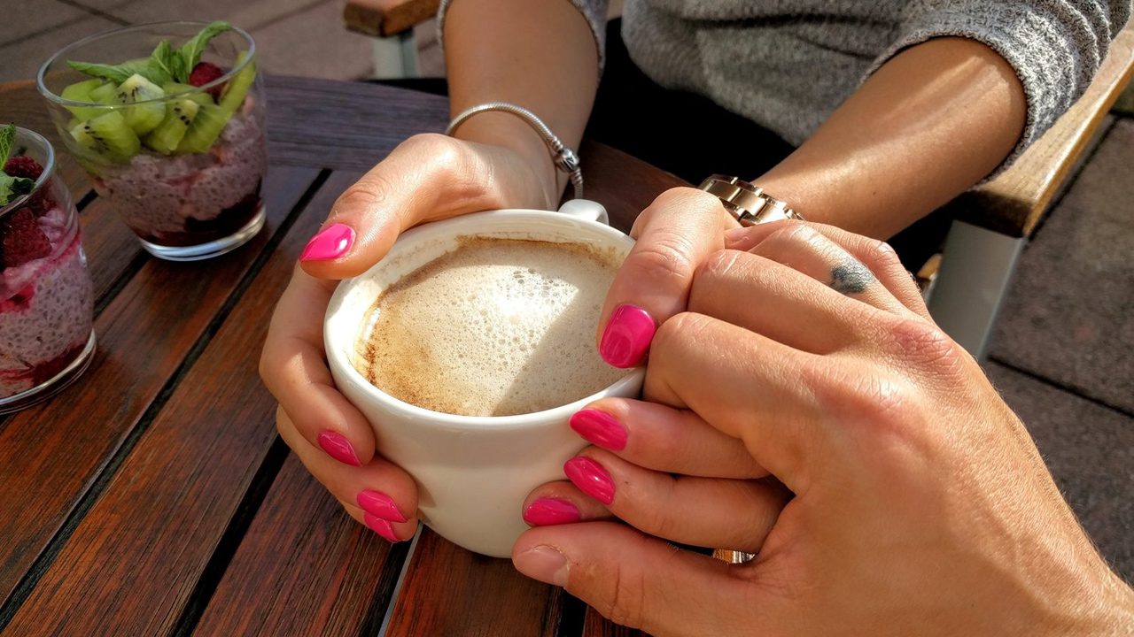 A couple holding hands at a coffee shop