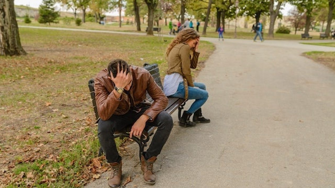 Couple upset at each other on a park bench