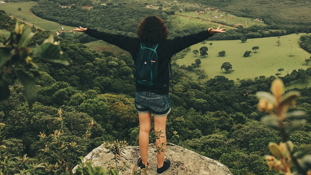 Person standing on the edge of a mountain with arms up