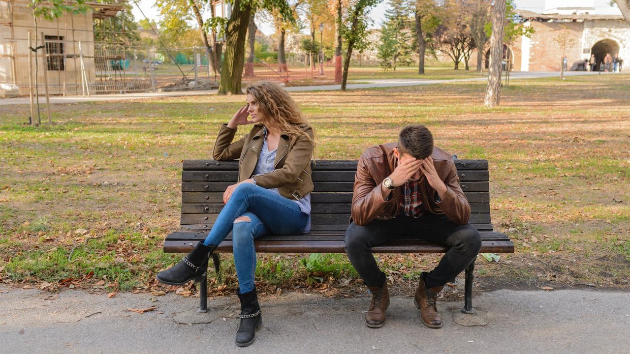 Couple arguing on a park bench about an affair