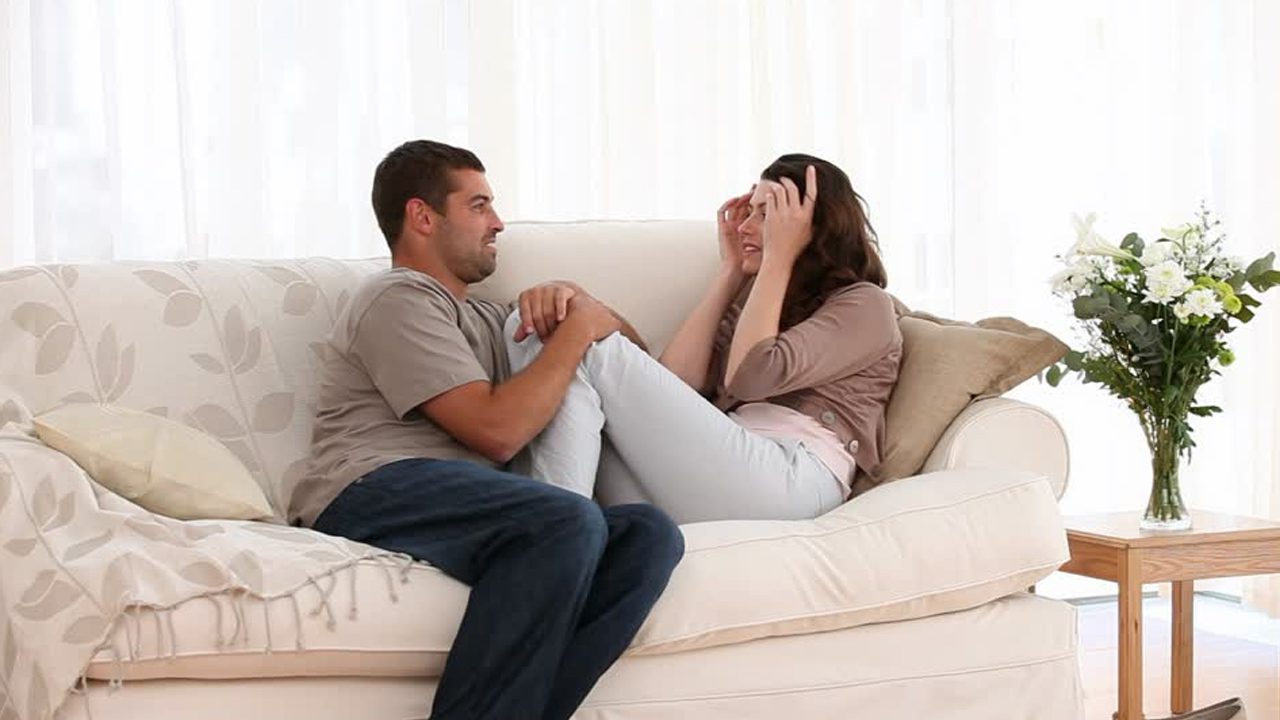 Engaged couple sitting on the couch talking